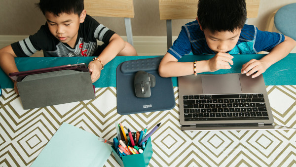 Overhead shot of two young boys working on laptop and tablet at table