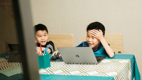 Two boys working on laptop and tablet at table