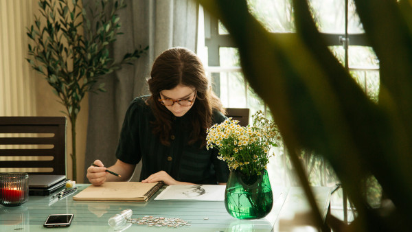 A young student sketching at her dining room table