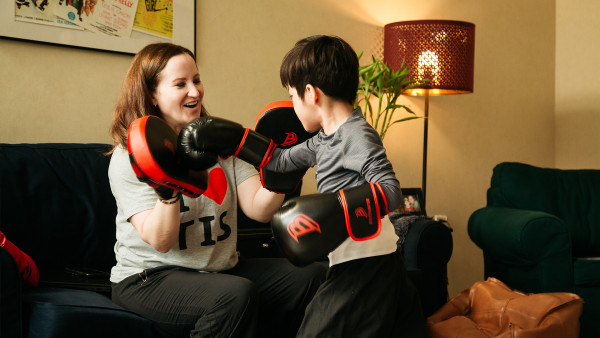 Mother and son wearing boxing gloves and practicing martial arts at home